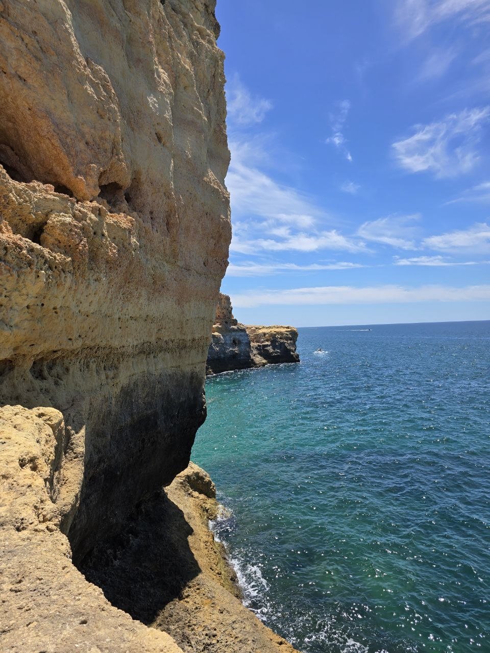 Tall limestone cliff face above clear blue water