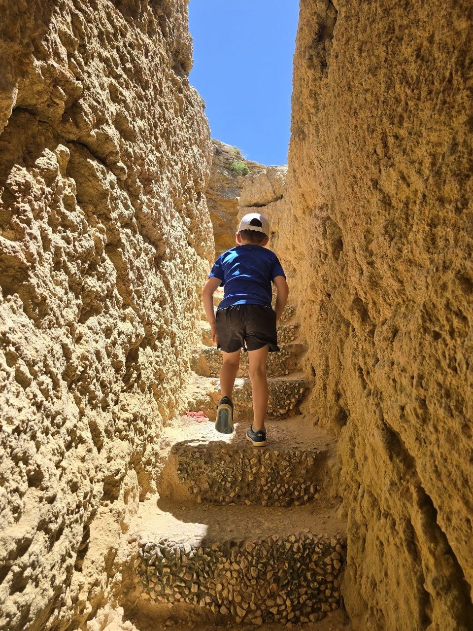 Noah climbing narrow stone stairs between limestone walls