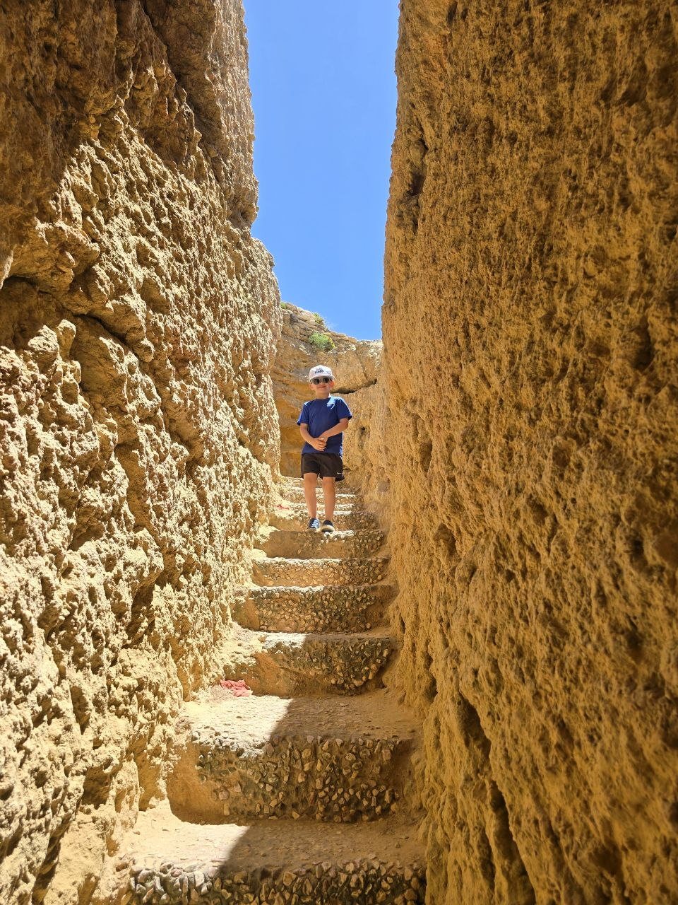 Noah standing on narrow stone stairs between limestone walls