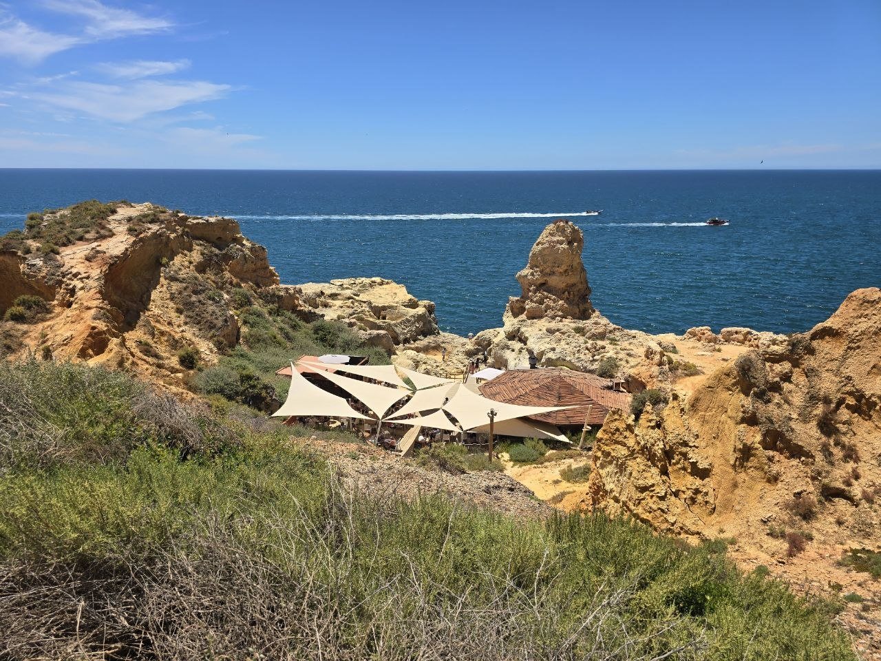 Boneca Bar tucked below golden cliffs with blue ocean beyond