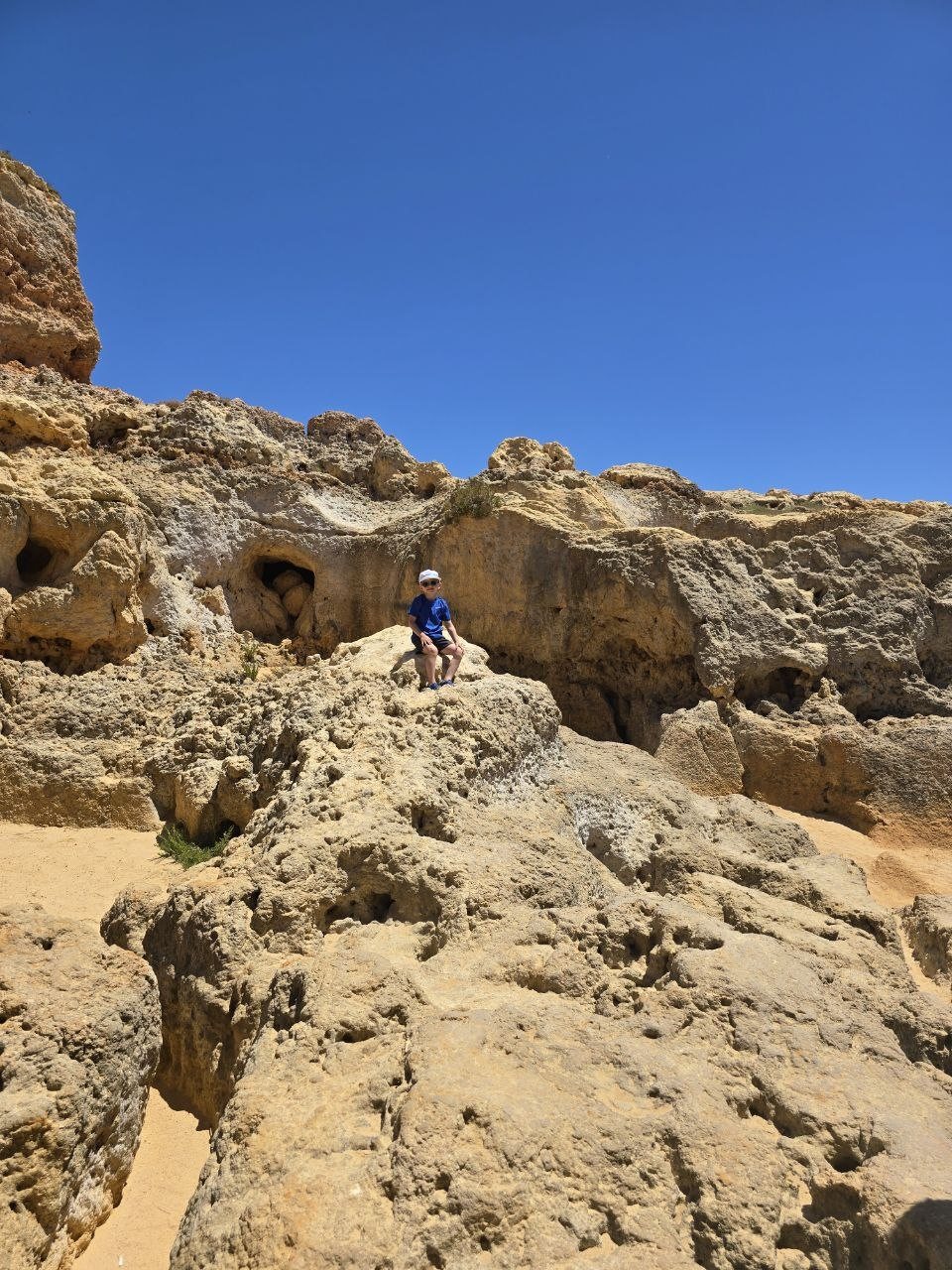 Noah sitting on rough golden limestone rocks near Boneca Bar