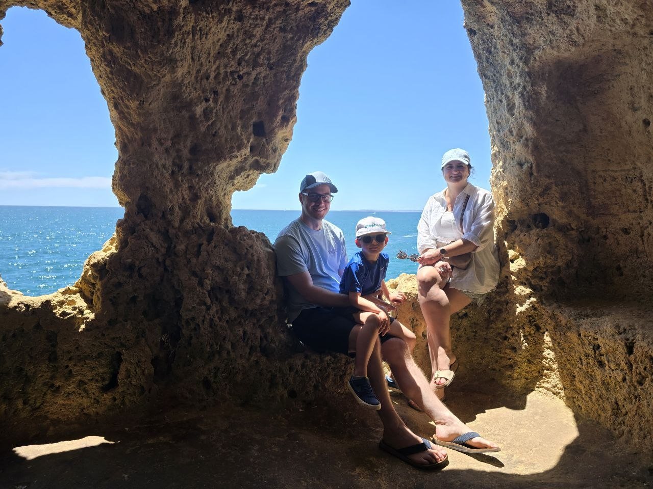 Family sitting inside a sea-cave window with ocean behind