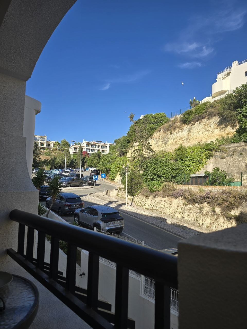 View from the condo balcony over a quiet street and sunny Algarve cliffside buildings