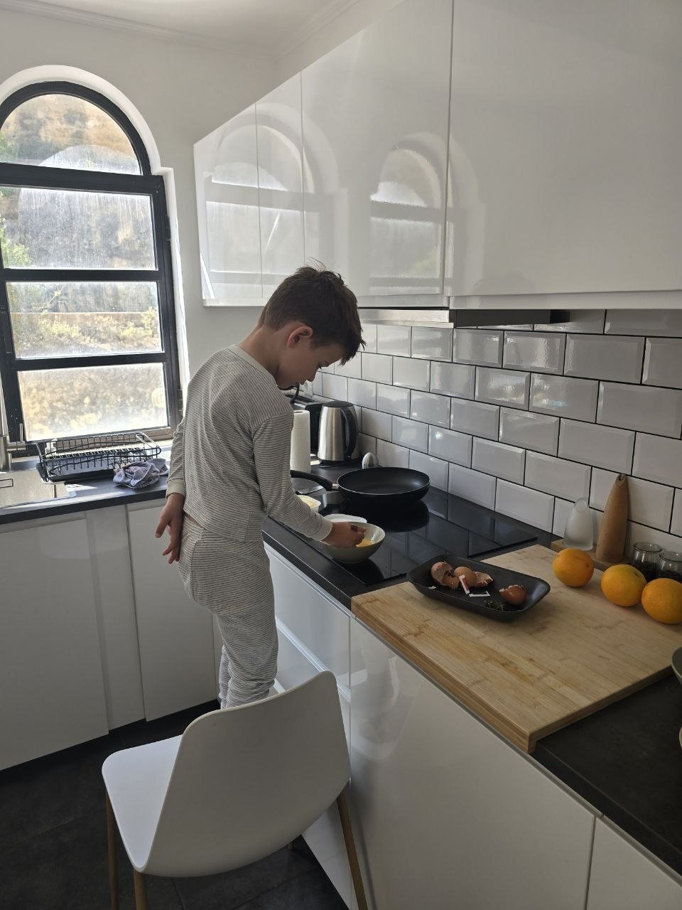 Noah standing on a kitchen chair cooking scrambled eggs in the condo kitchen