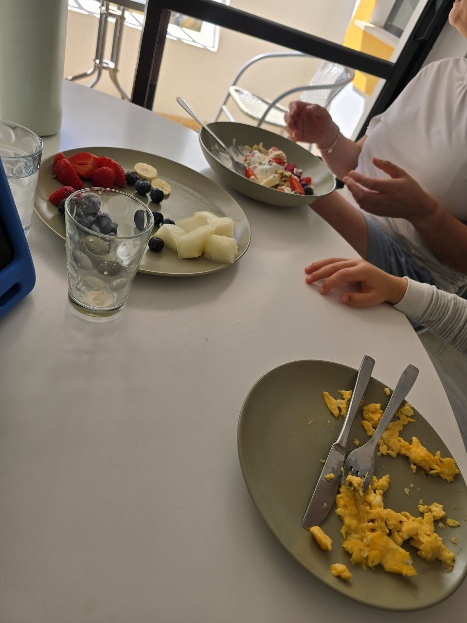 Breakfast table with scrambled eggs, fruit, yogurt, berries, and orange juice