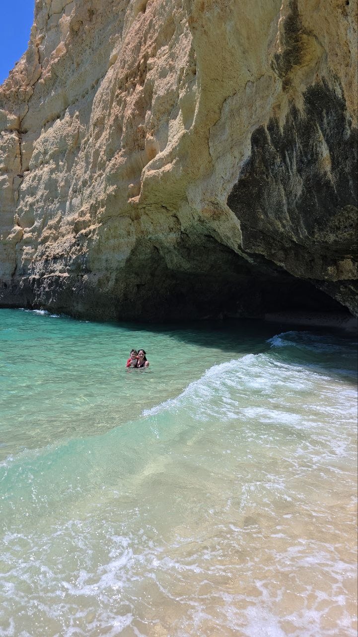 Catherine and Noah swimming together beside a sea cave at Vale de Centeanes Beach