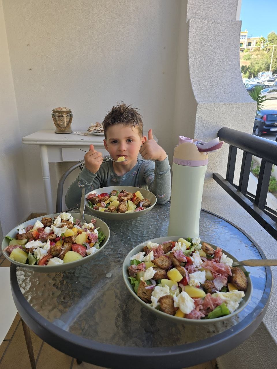 Noah giving two thumbs up while eating salad dinner on the condo terrace