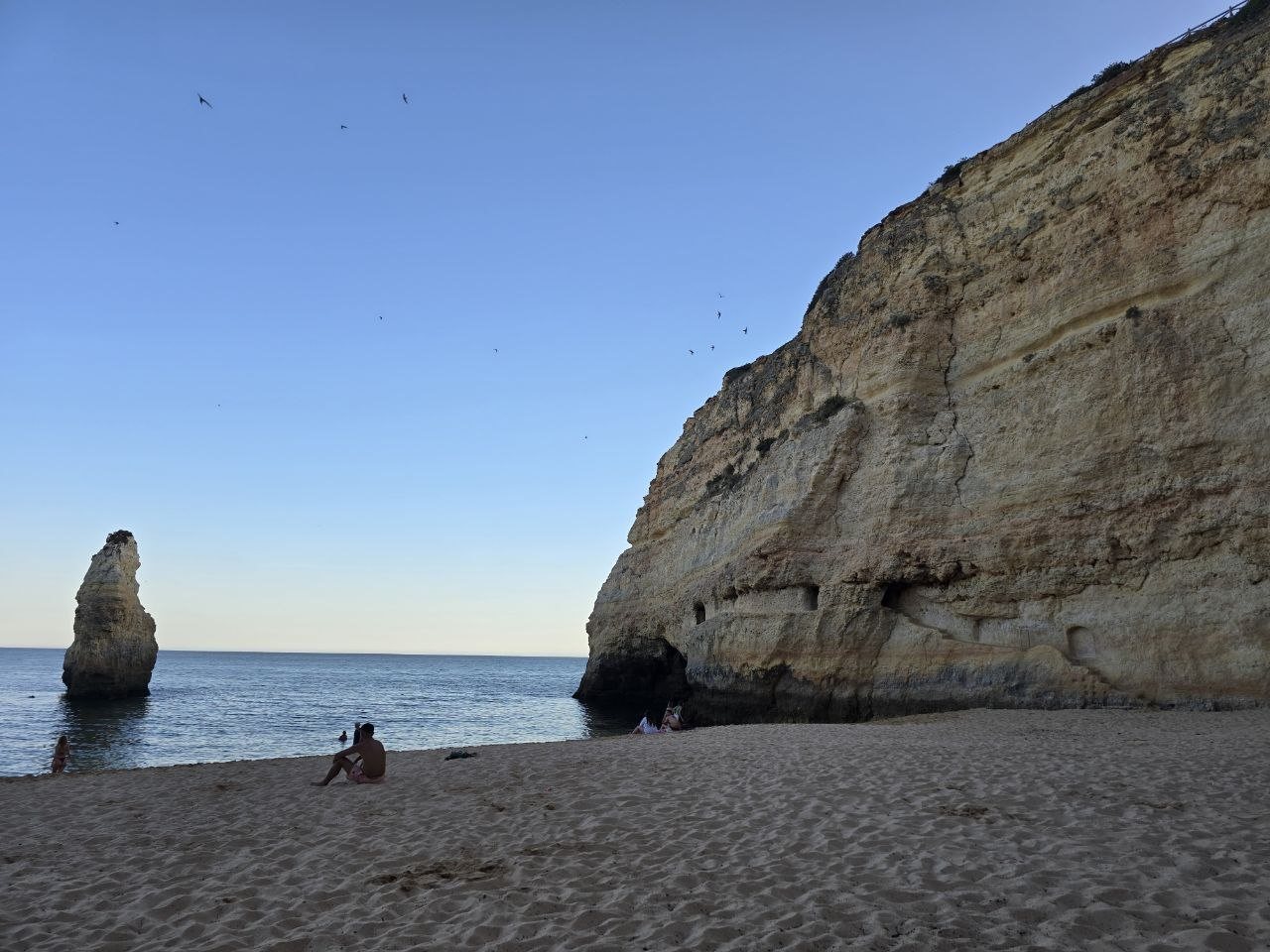 Praia do Carvalho beach with a sea stack, calm ocean, sand, and tall golden cliff