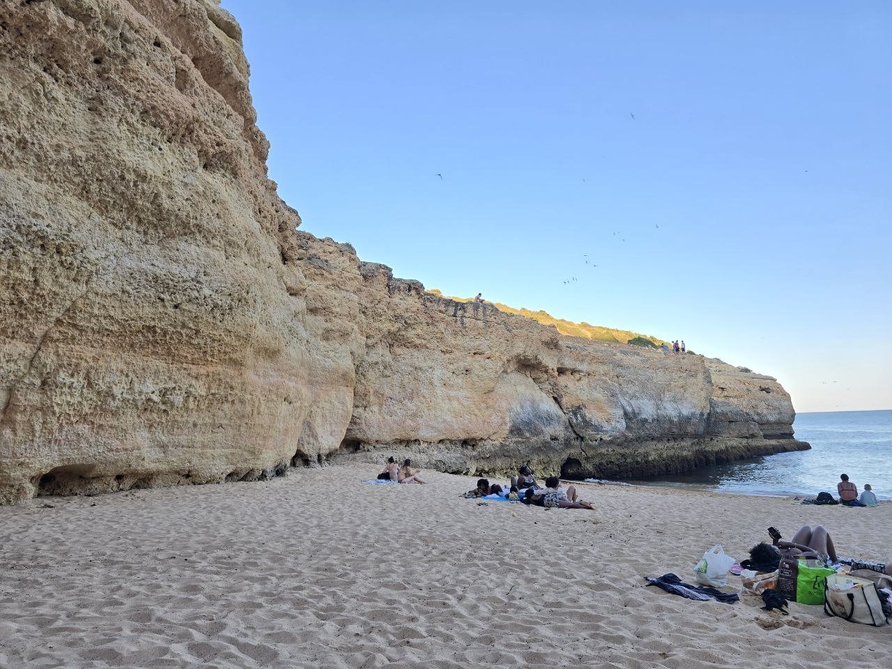 Wide view across Praia do Carvalho sand, cliffs, and calm water