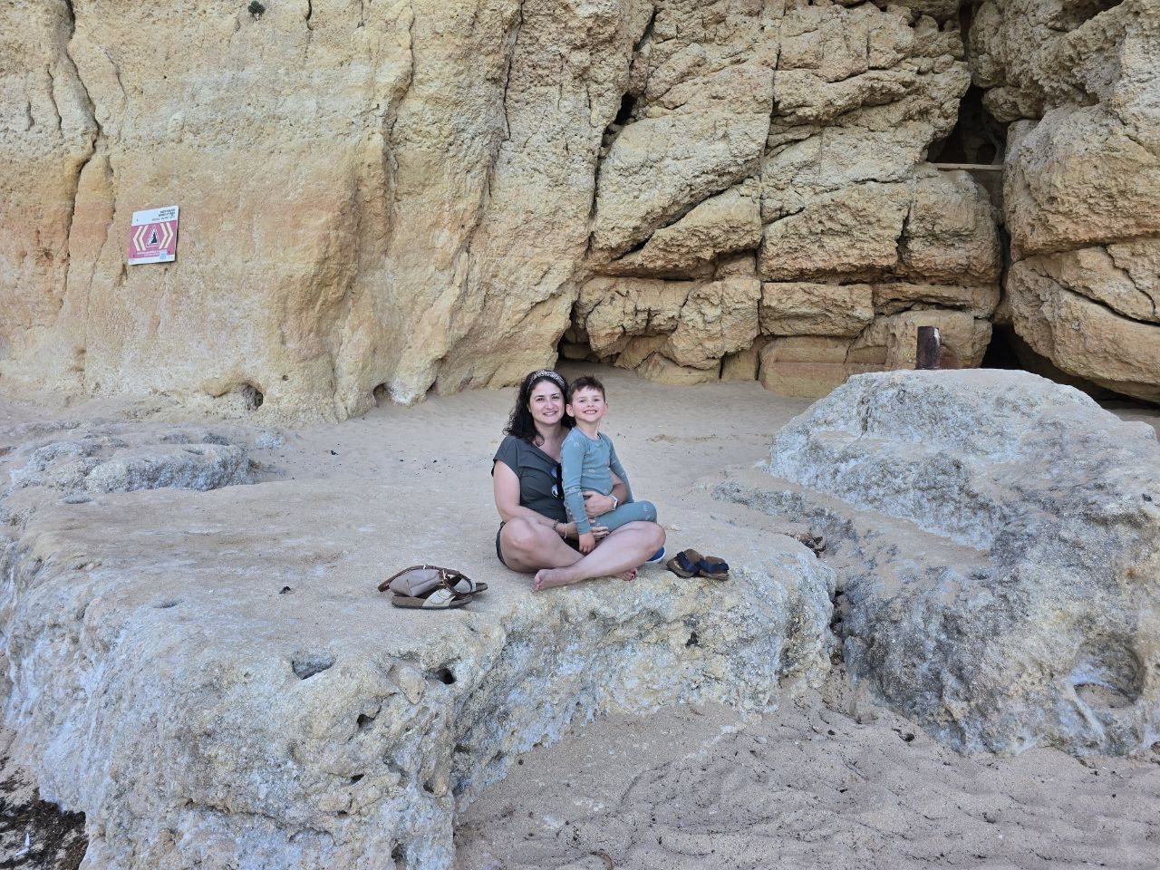 Catherine and Noah sitting together on rocks at Praia do Carvalho