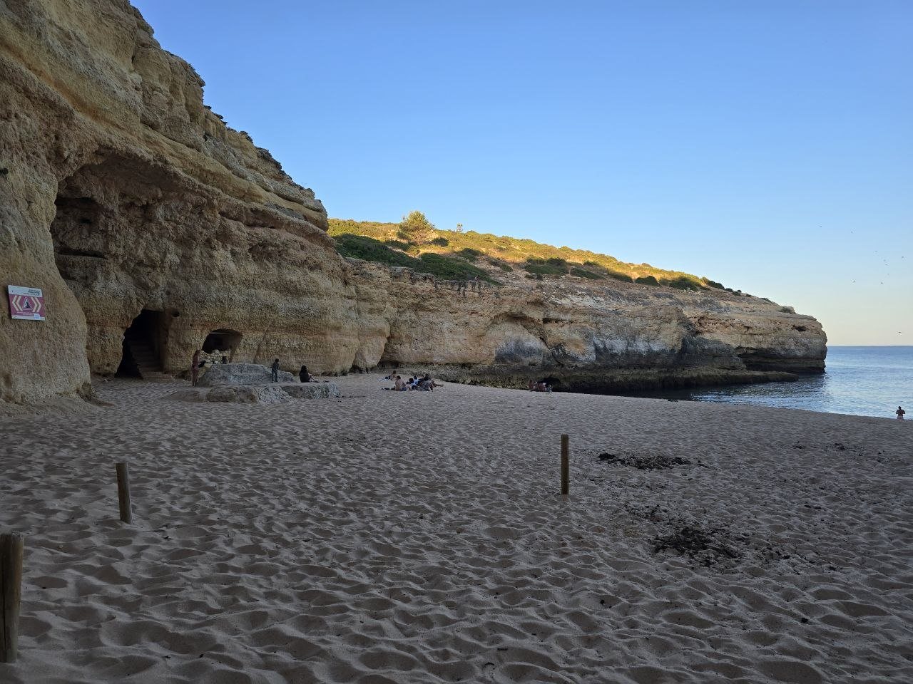 Wide sandy Praia do Carvalho beach with cave entrances and cliffs