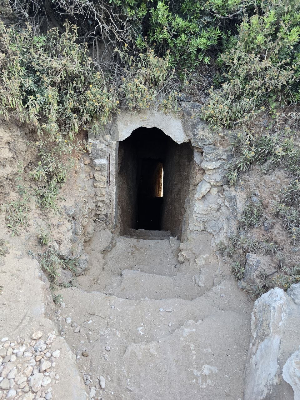 Small tunnel entrance carved into the cliff above Praia do Carvalho
