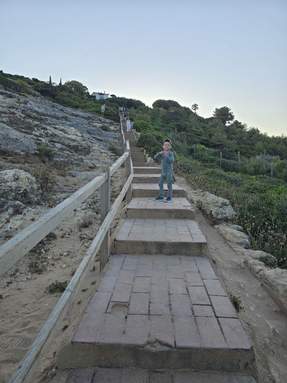 Noah standing on the long stairs up from Praia do Carvalho at sunset