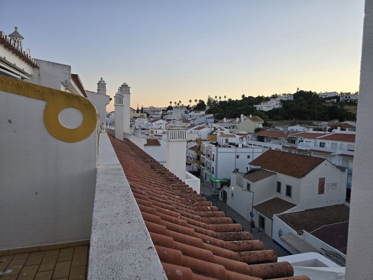 Rooftop terrace view over Carvoeiro white buildings, red tile roofs, and sunset sky