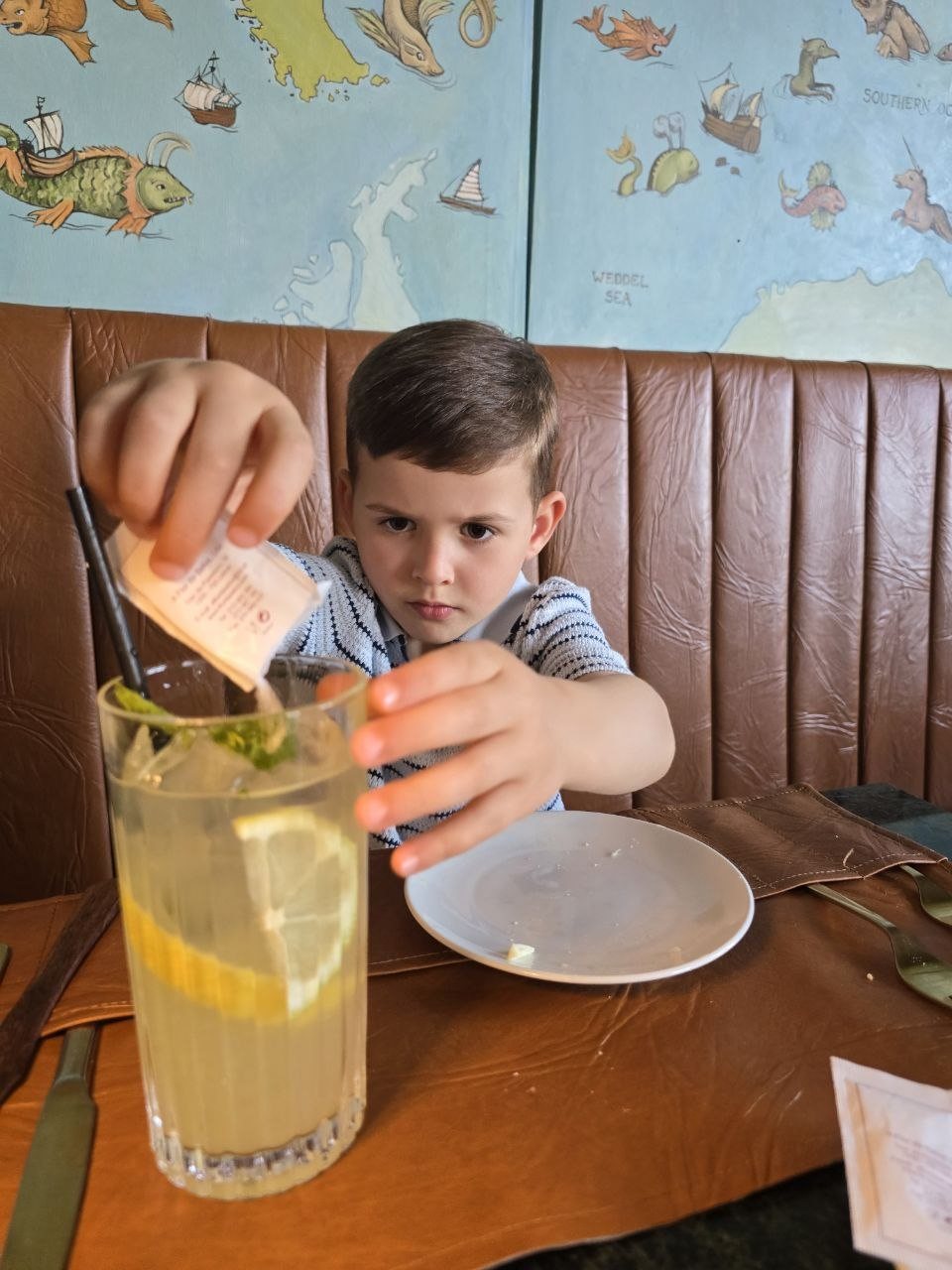 Noah stirring a tall lemon and mint drink at the restaurant table