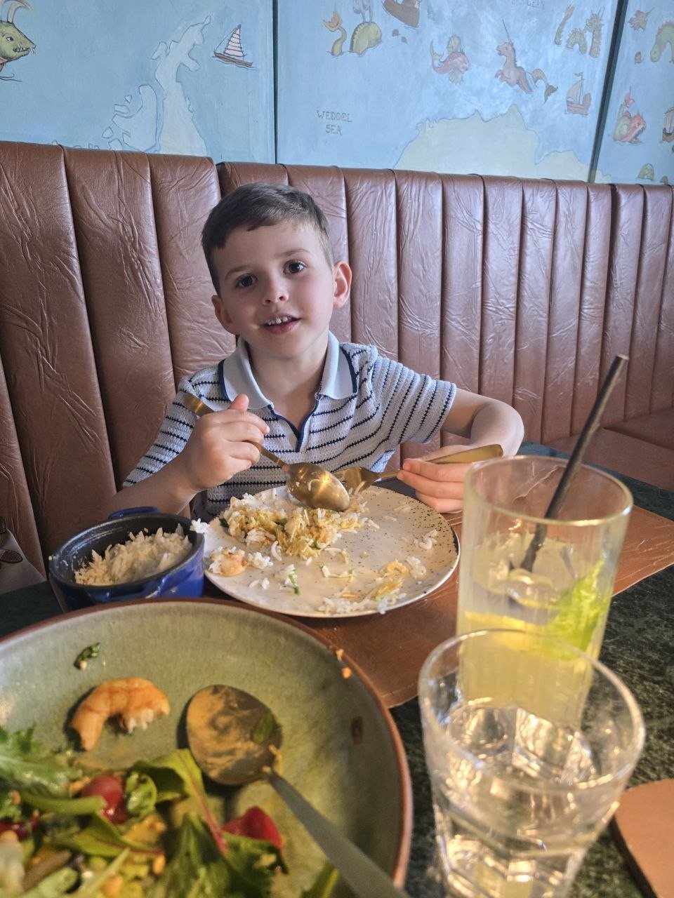 Noah holding a fork beside his dinner bowl at Geographia
