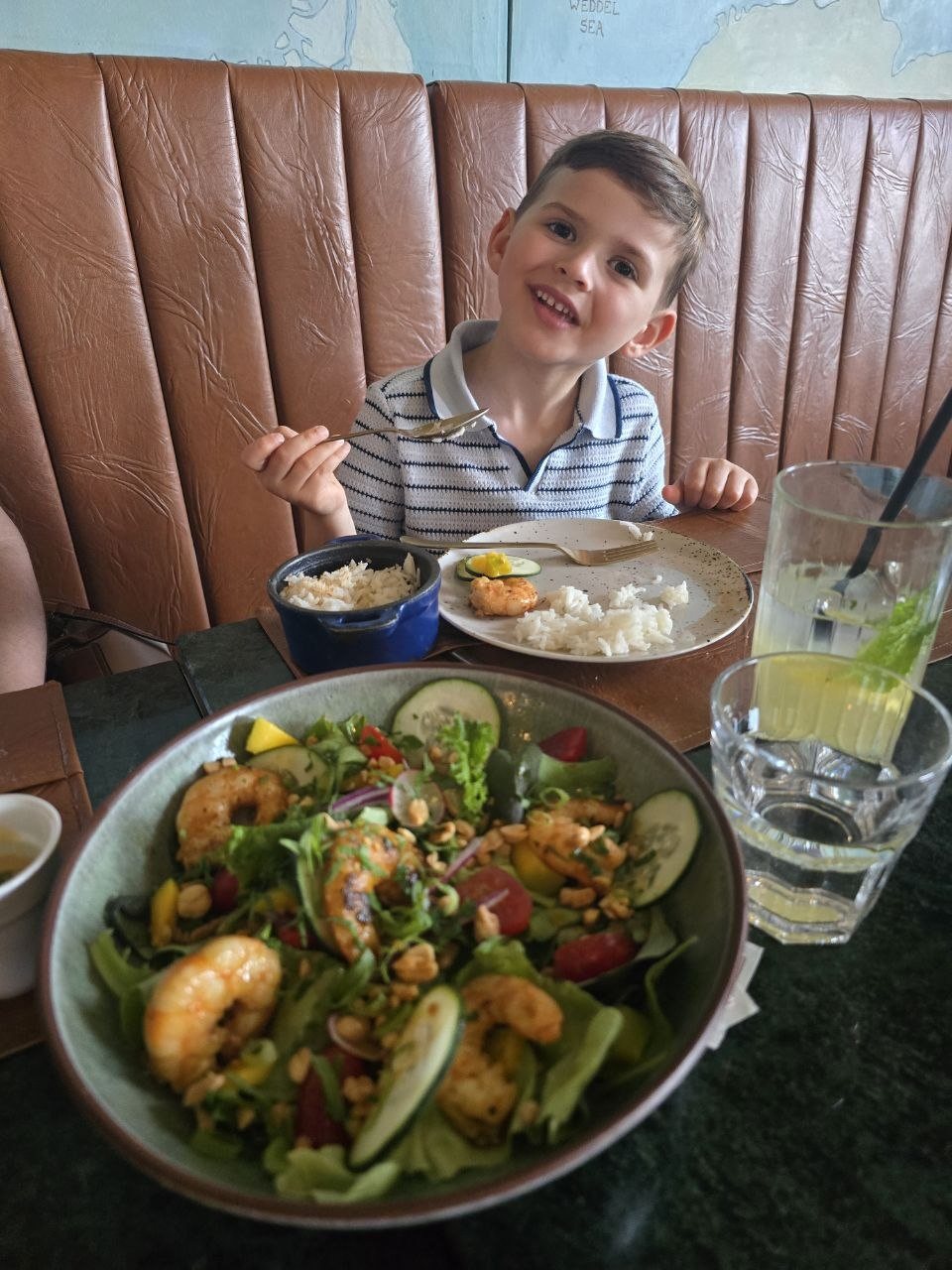 Noah smiling at dinner with a shrimp salad and rice bowl on the table