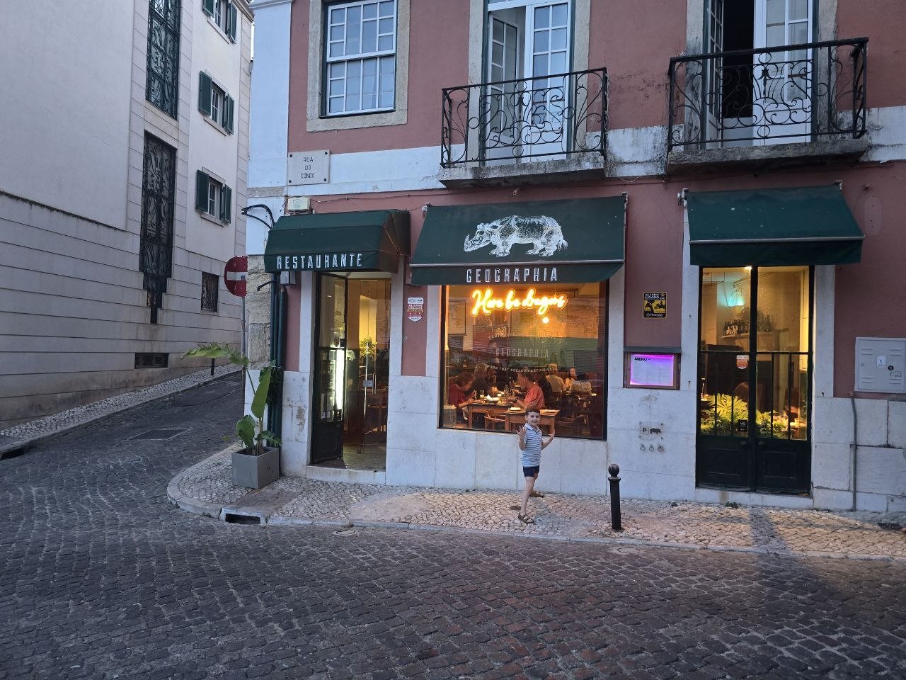 Exterior of Restaurante Geographia on a Lisbon cobblestone street with Noah posing outside