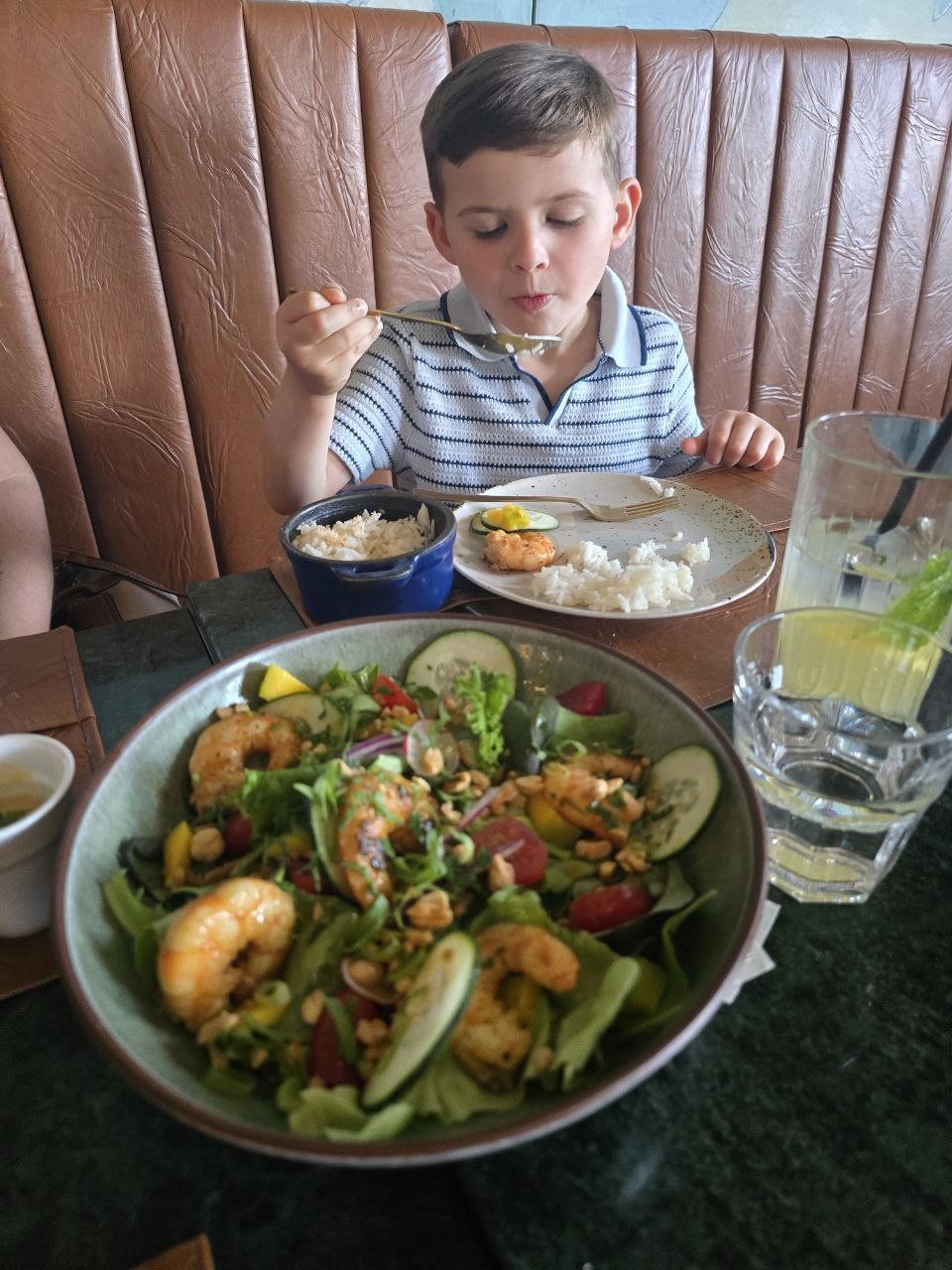 Shrimp salad in the foreground with Noah eating rice behind it