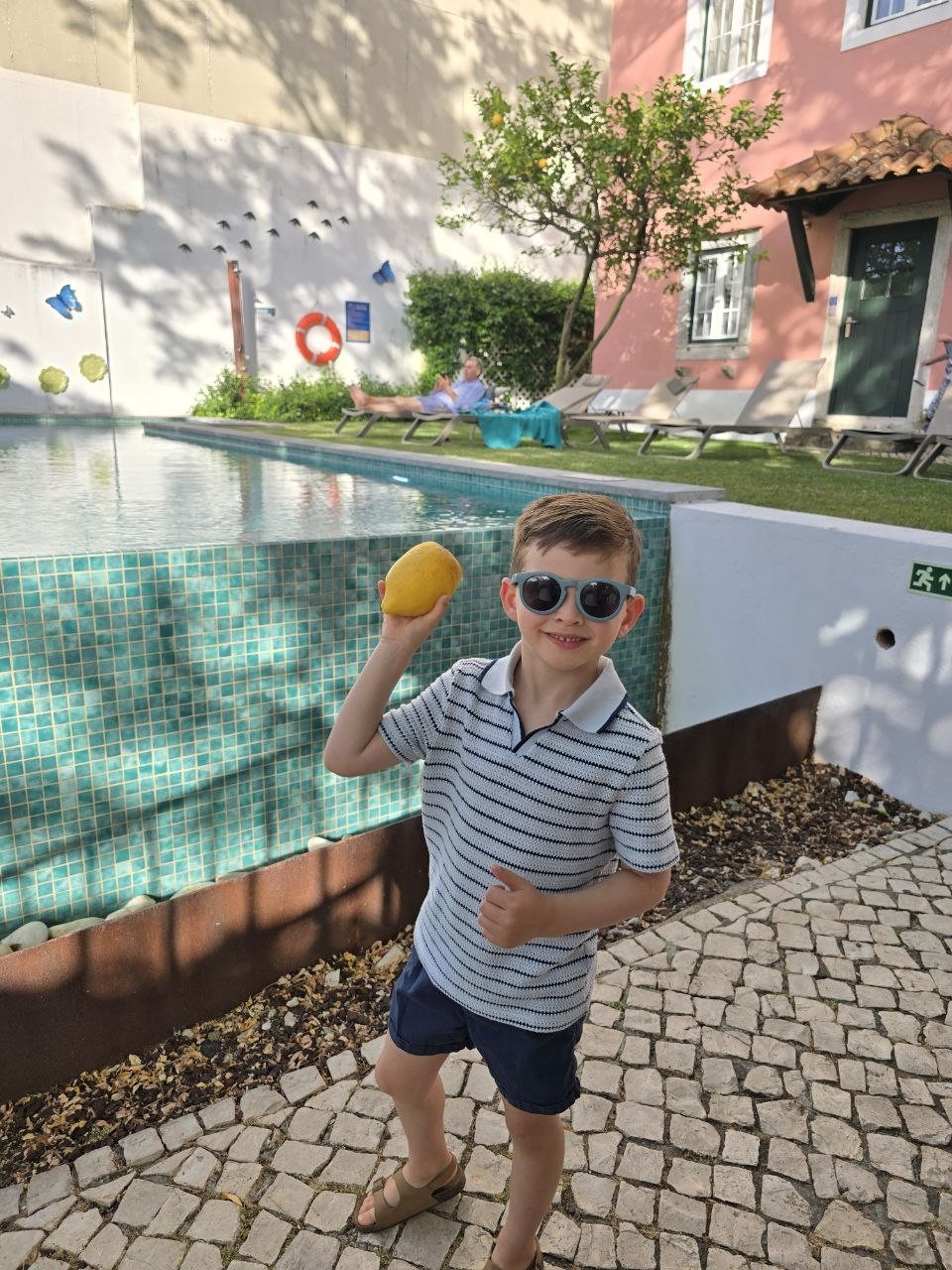 Noah holding a fresh lemon beside the Jardim da Lapa pool