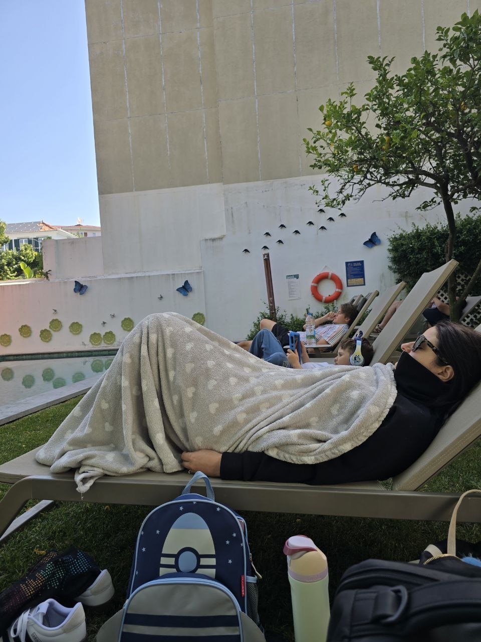 Family resting on pool loungers at the Lisbon hotel after the overnight flight